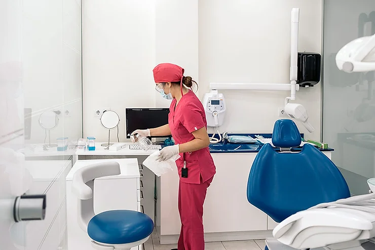A lab assistant in pink uniform spraying disinfectant on her desk